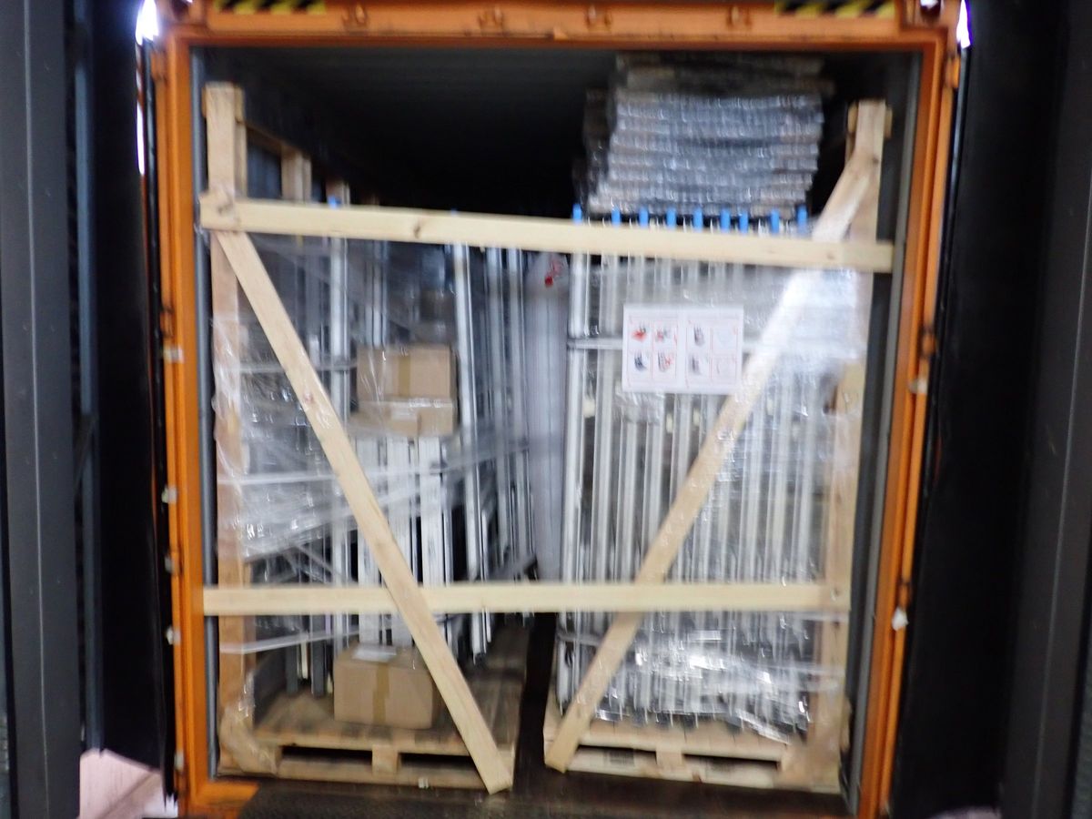 A shipping container at the factory, loaded with two braced and wrapped racks of windows