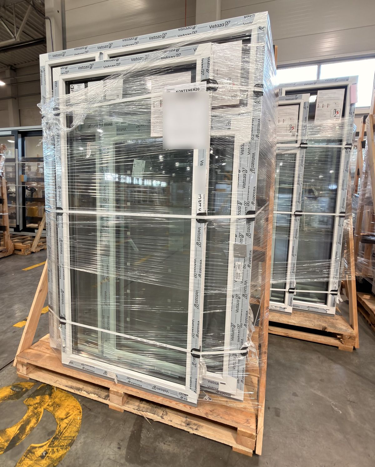 Finished units at the factory, standing on their rack: braced, strapped over edge protectors and wrapped, with the container label on the front.