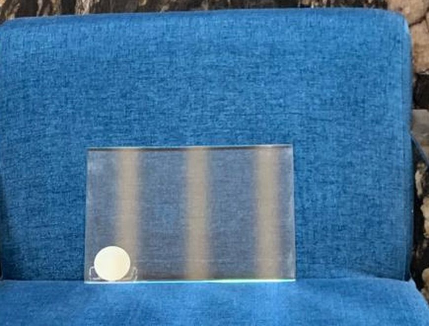 A sample of the coated glass, stood against dark fabric