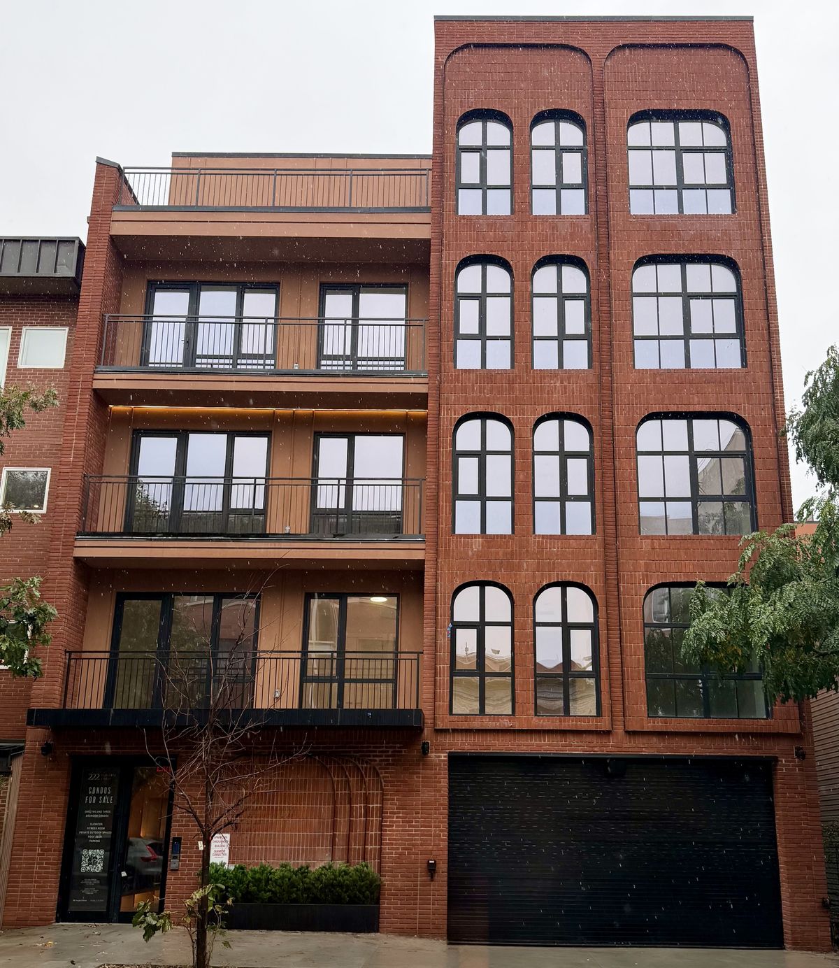 A flush red-brick bay of radius-headed black windows beside a roof terrace, on a Brooklyn condominium