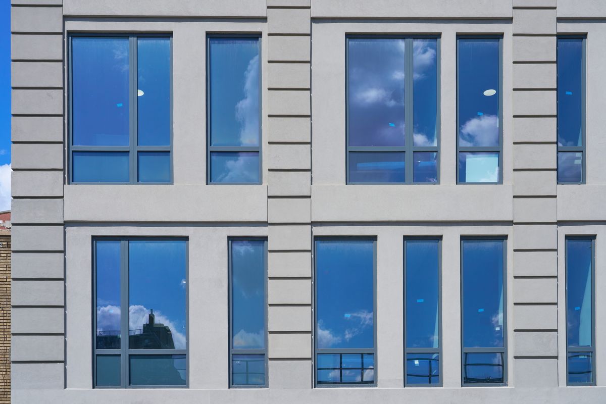 Five windows in a pale stucco wall: clear glass above the transom, black spandrel glass in the lower lite of every window