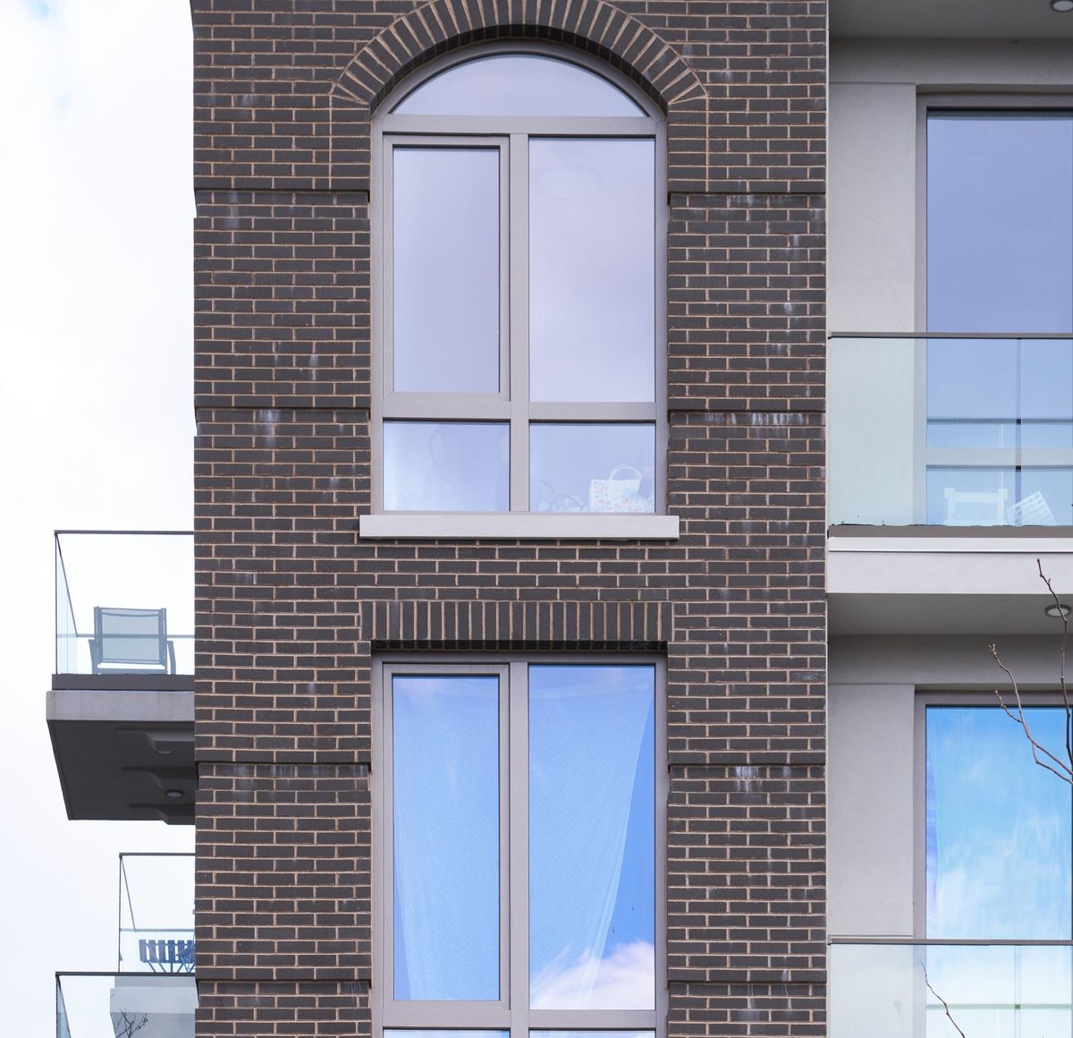 A round-top window on a brick facade: an arched fixed head over a rectangular window below