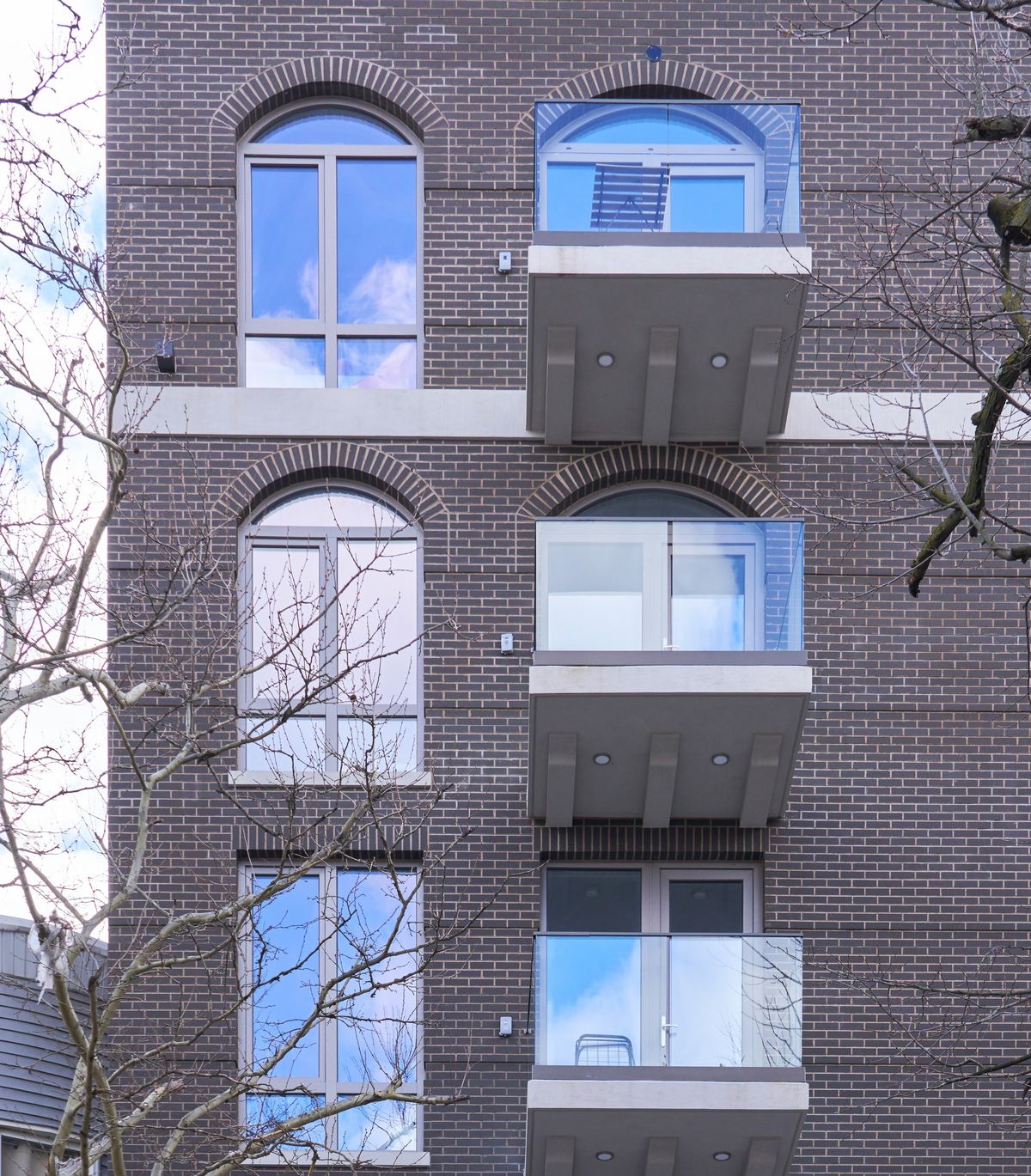 Arched window heads stacked up a brick elevation beside the balconies