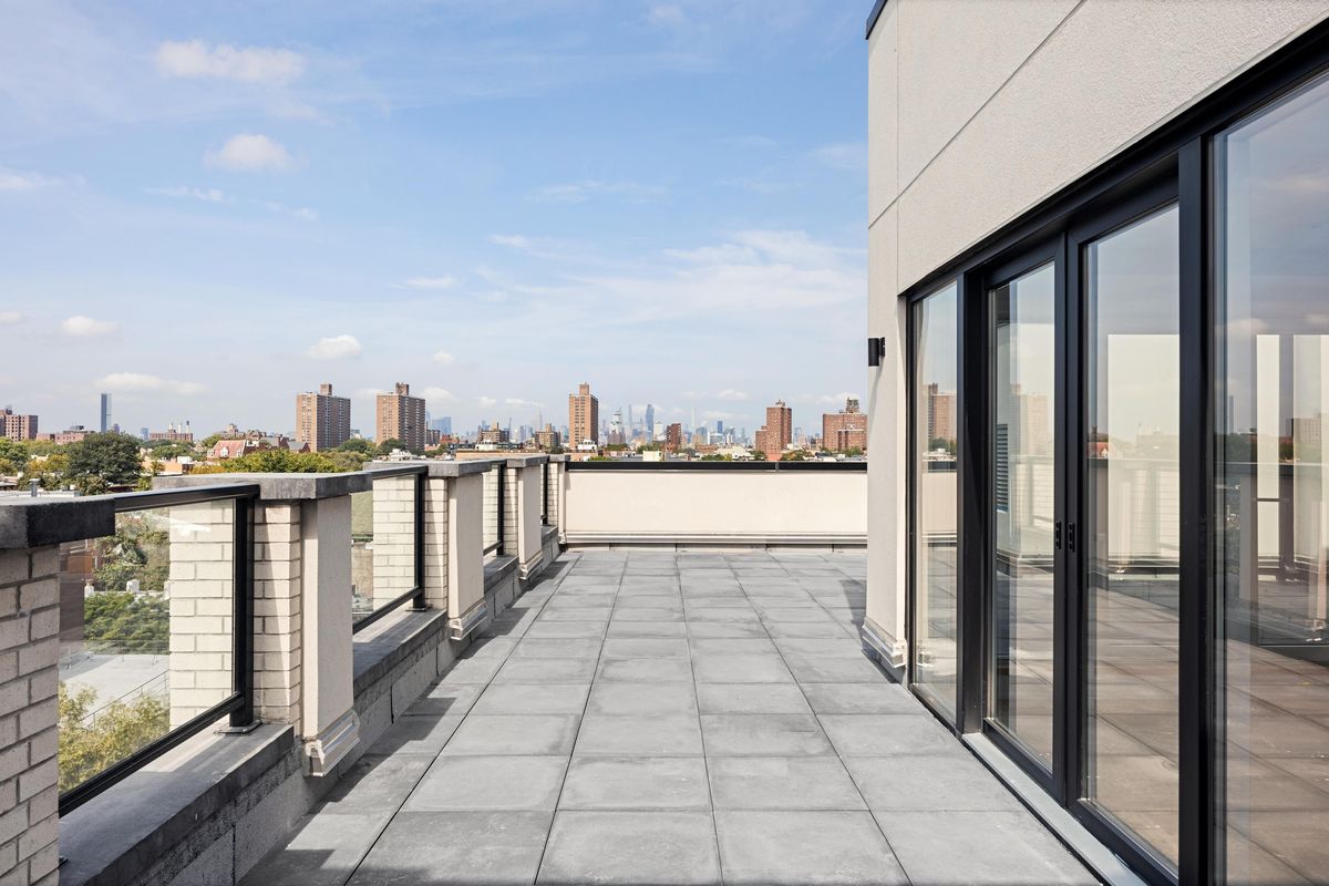 The sliding doors seen from the terrace, black frames against a pale wall, the skyline behind