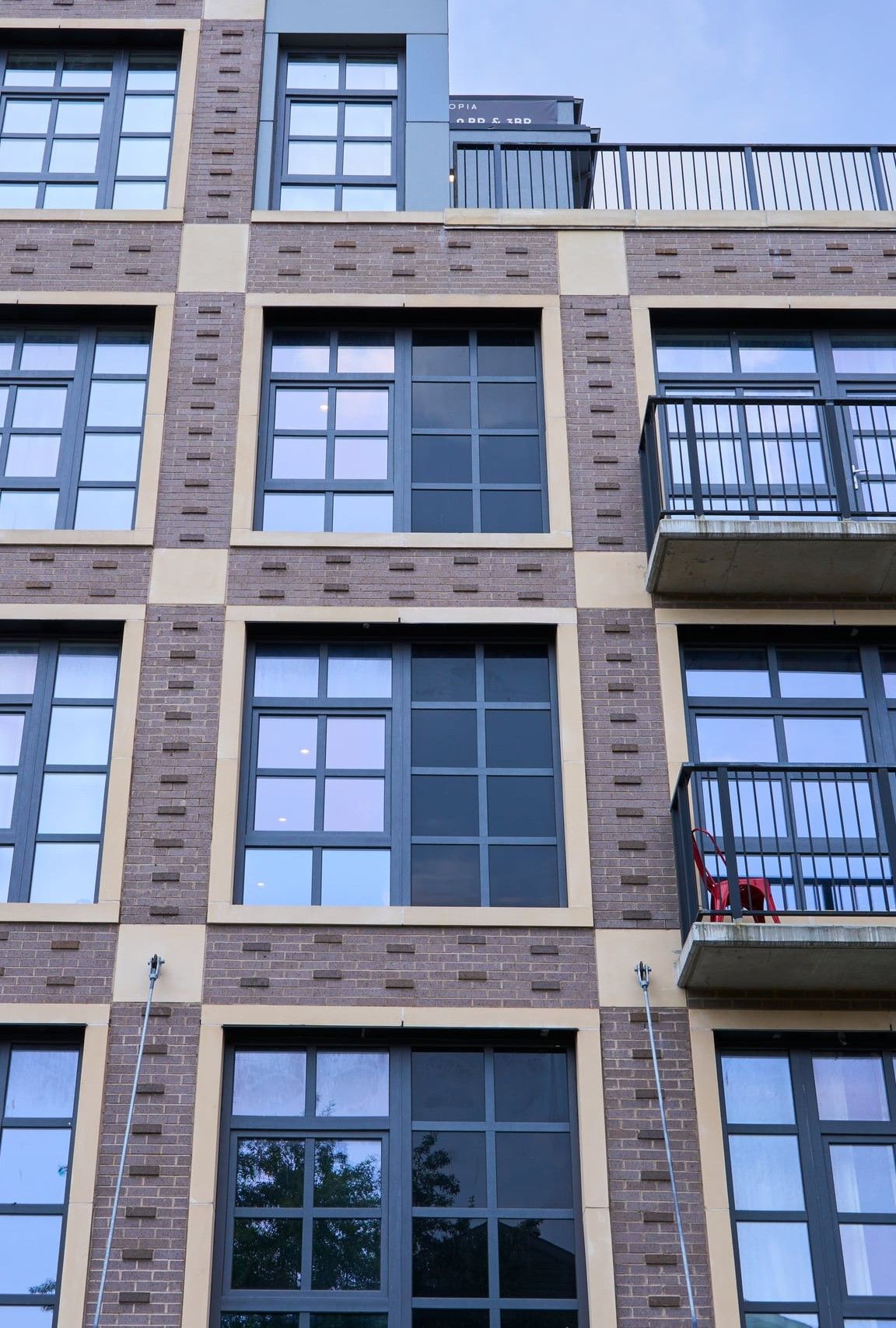 A column of black opaque spandrel glass between two columns of clear windows on a brick facade