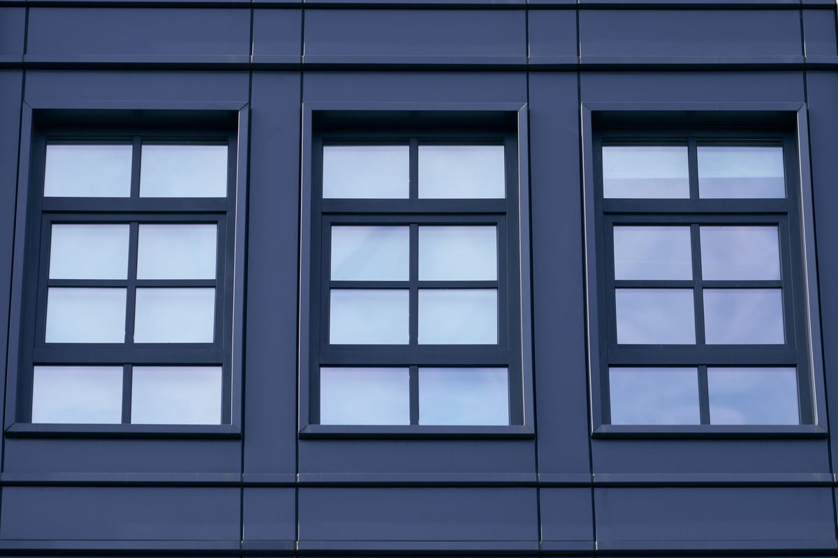 Three windows edge to edge in a dark metal band, each divided into six lights by black bars on the glass