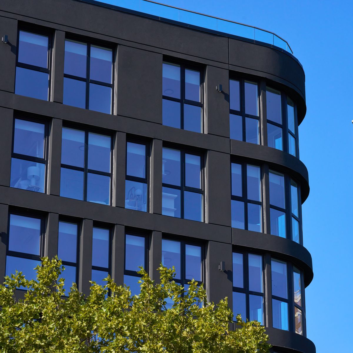 The curved corner of a building, black windows following the curve