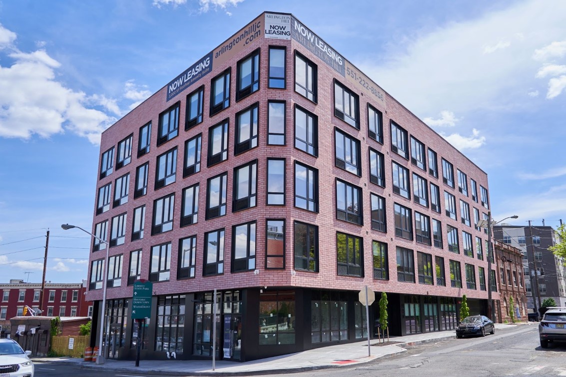 Corner view of a mid-rise brick building that highlights black trim and installed windows. Photo taken by the Vistaza team